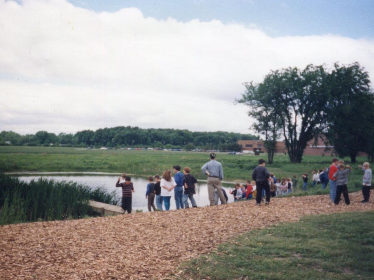 people gathered around the pond by the prairie