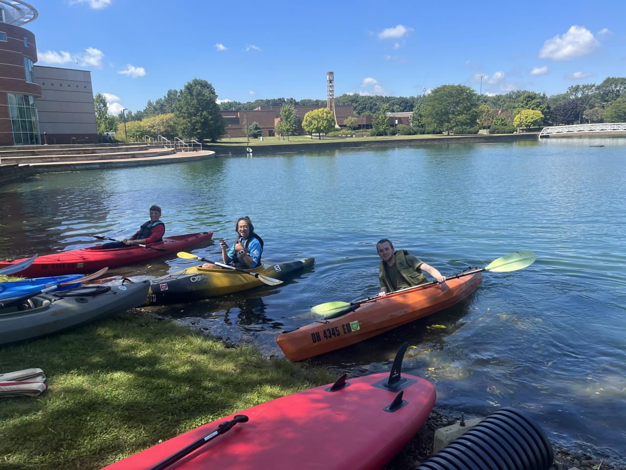 Three people in kayaks on campus pond