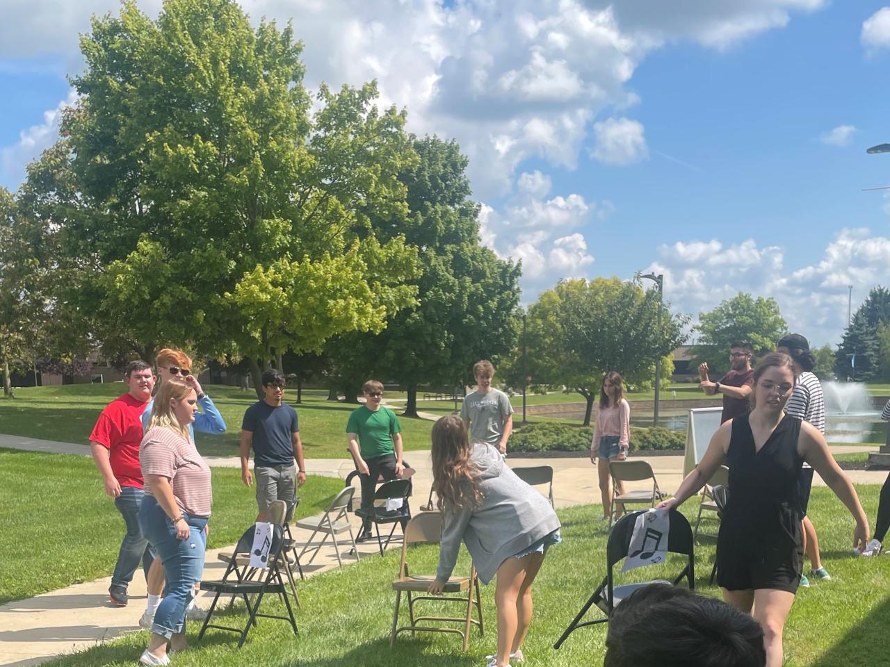 Young people playing musical chairs outside on a sunny day