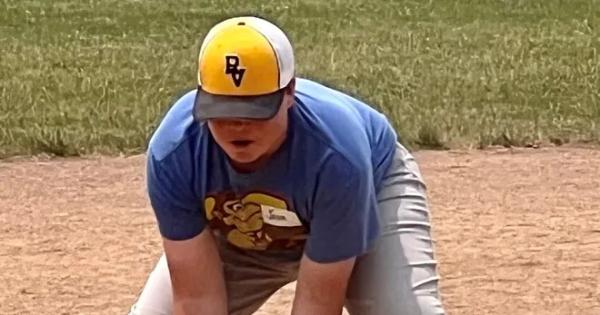 young baseball player in yellow and blue reaches down to make a catch
