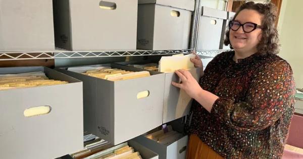 Woman in glasses looking through many file boxes