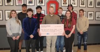 students posing with recipient of one of the checks