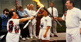 Woman lighting Olympic torch from male torch carrier