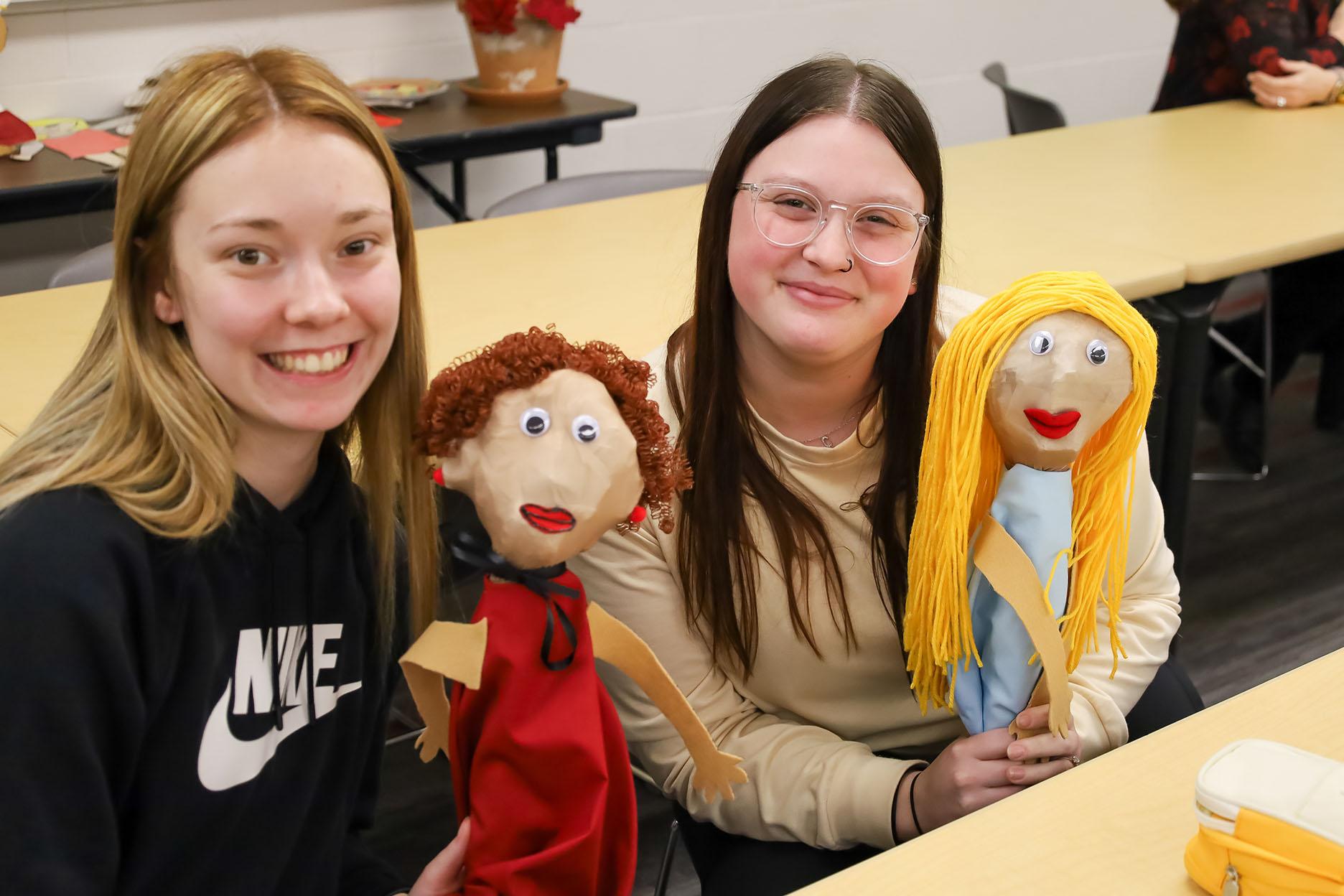 Two young women holding homemade puppets