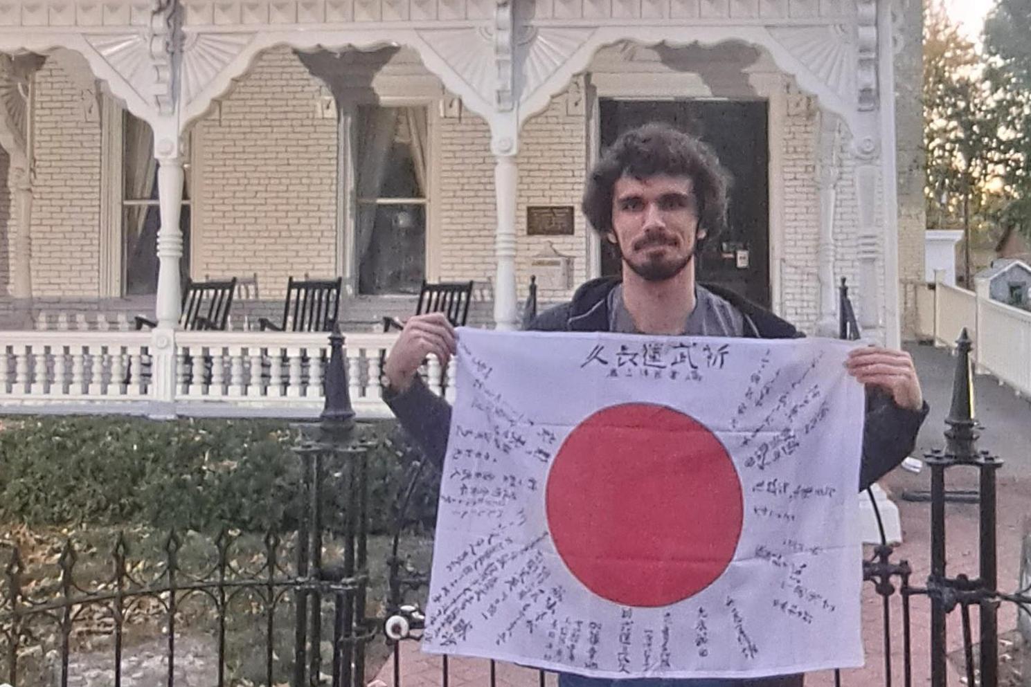 man holding flag with red circle in middle