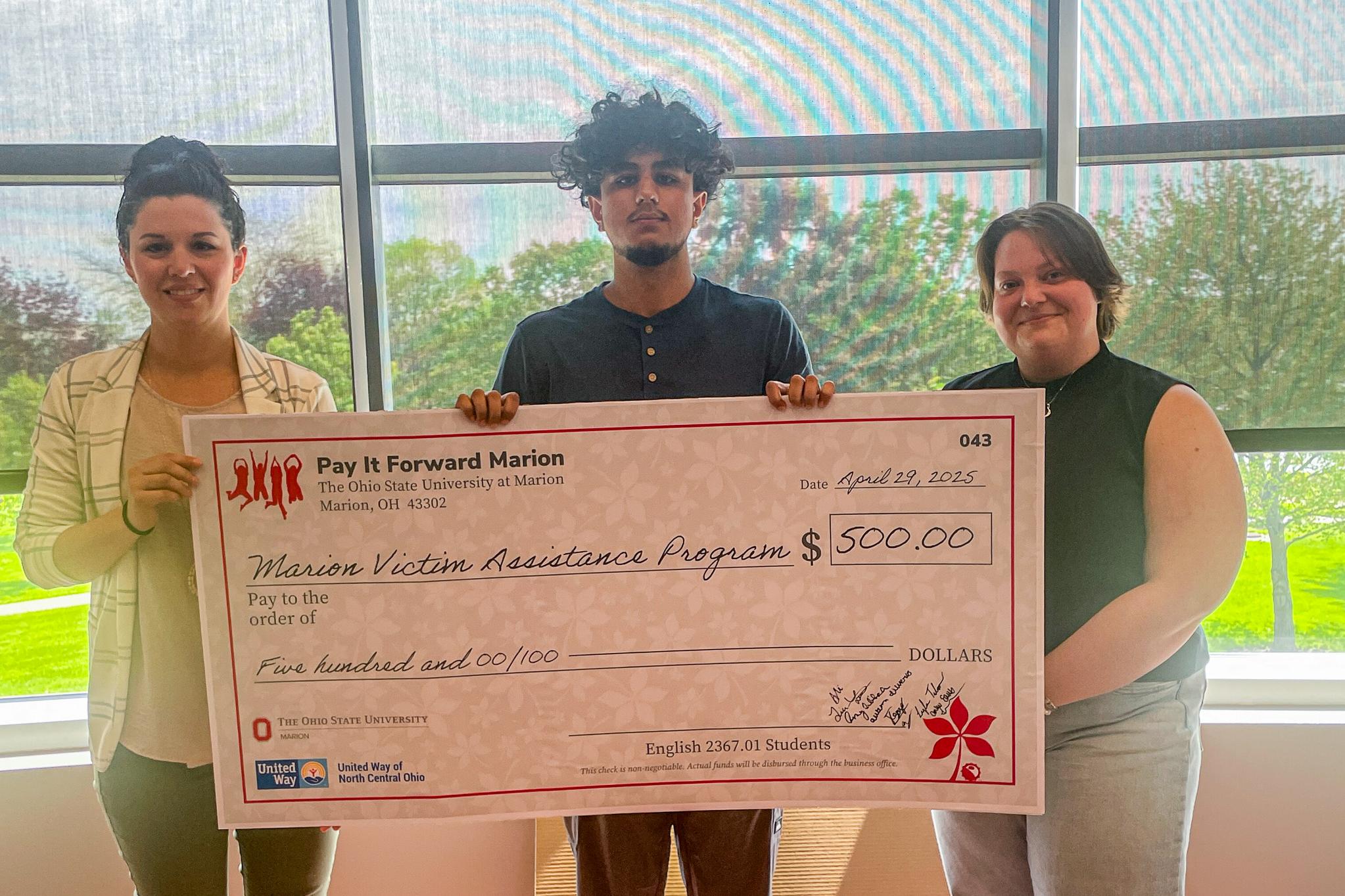 Group of 3 holding large check in front of window