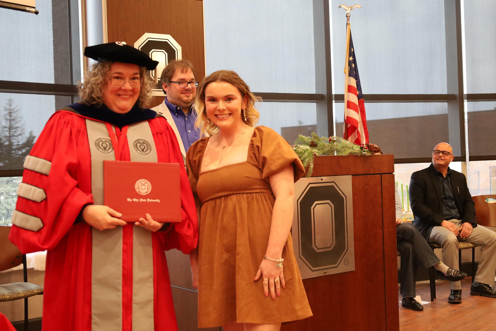 woman accepting diploma from university dean in academic regalia