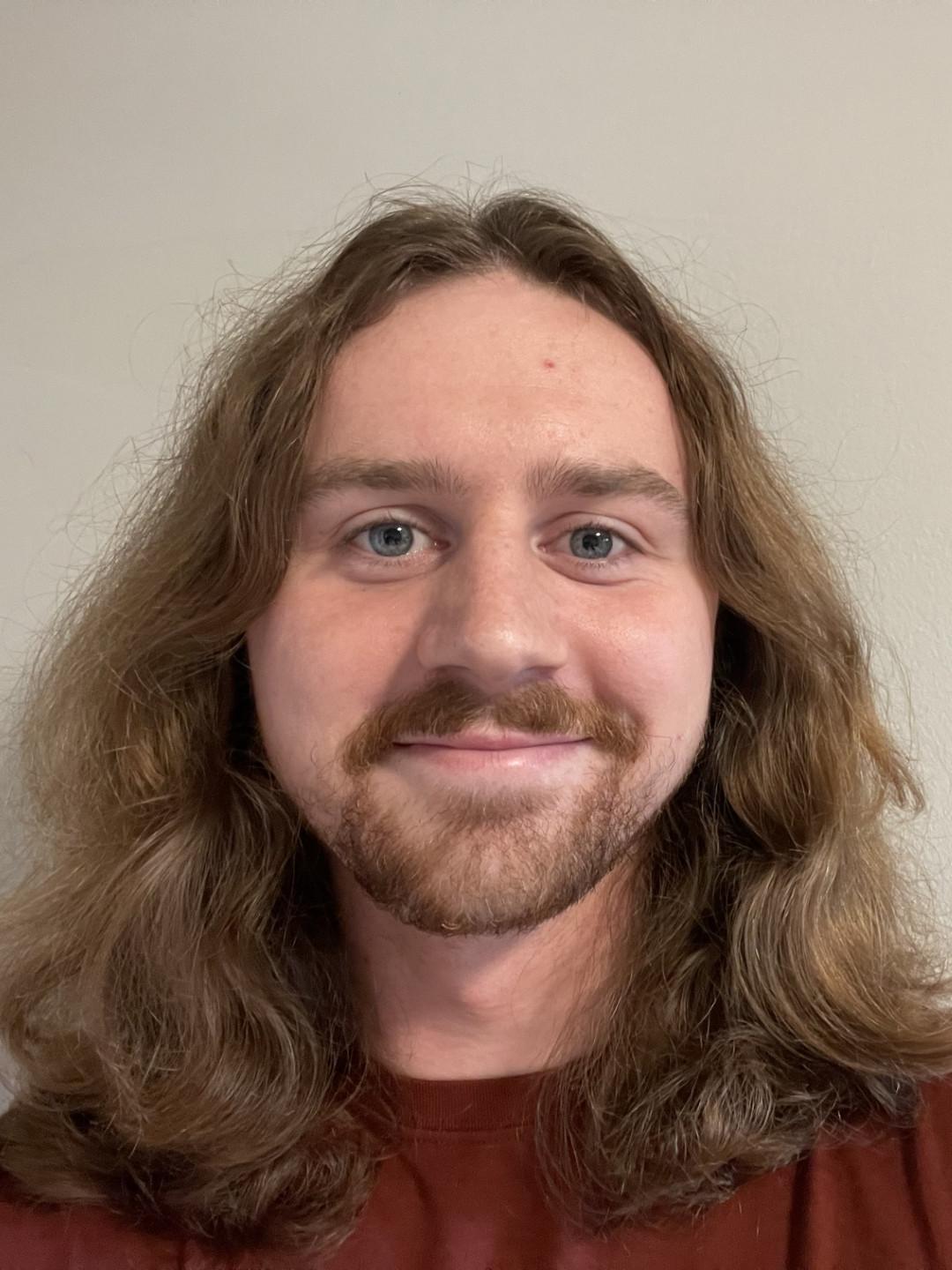 man with long hair beard and mustache in maroon shirt