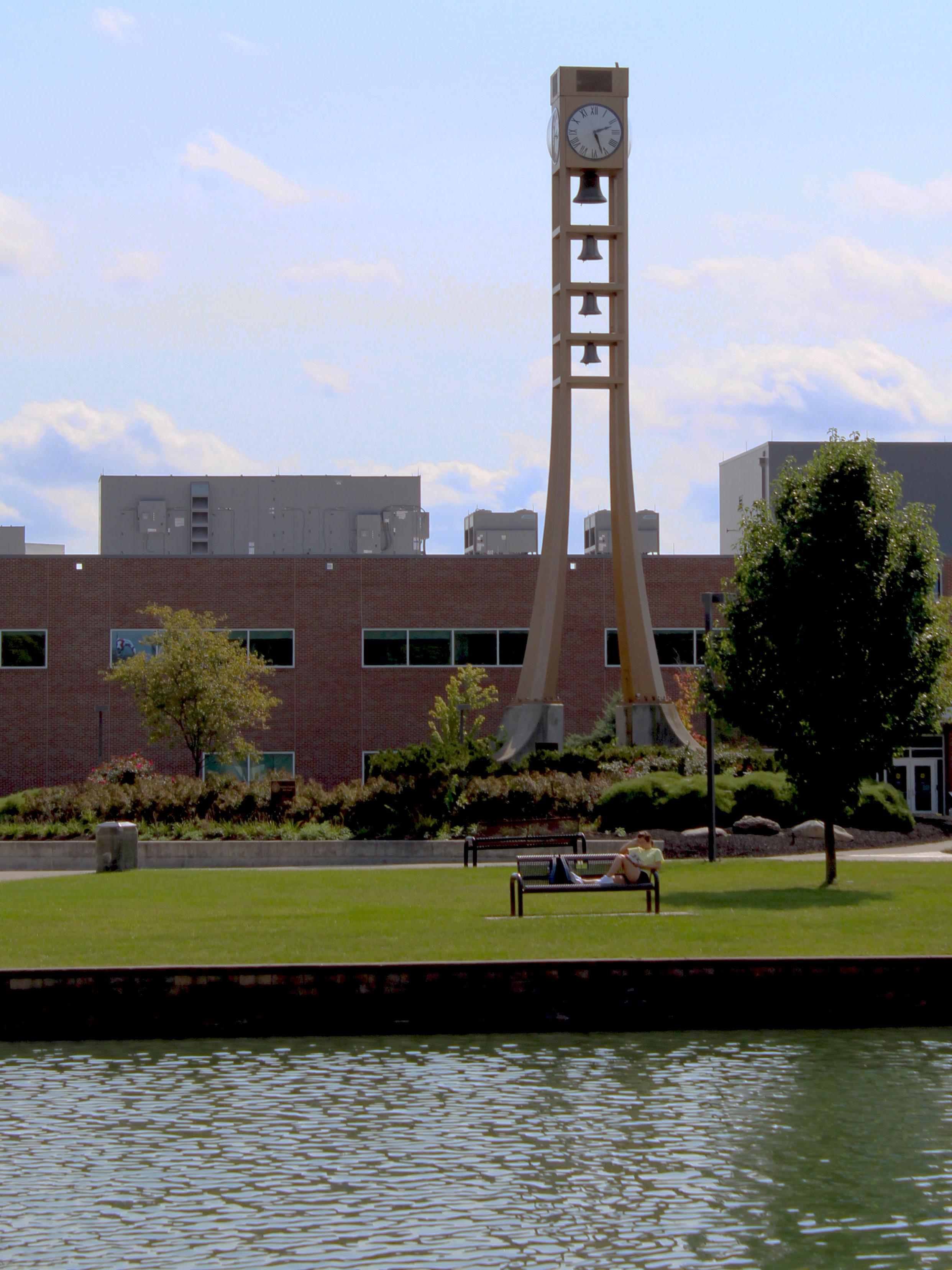 bell tower with clock over looking campus pond