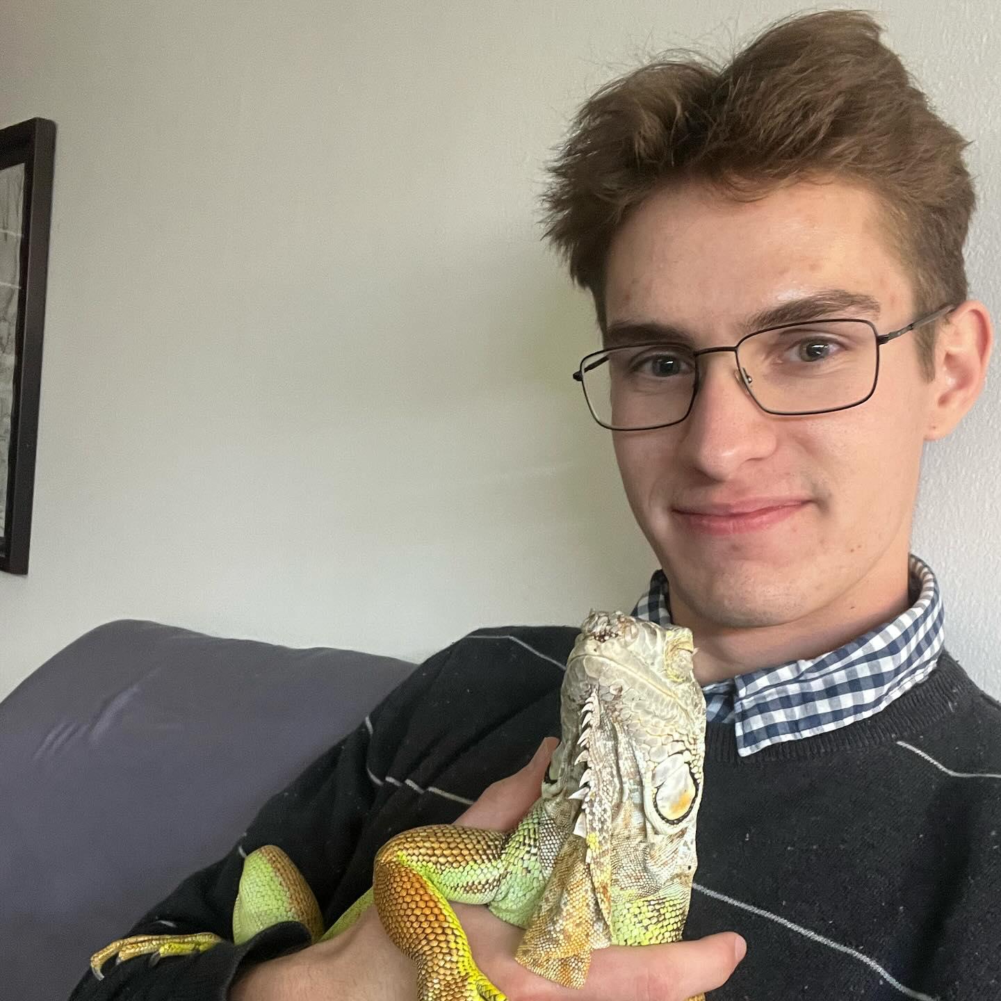 Young man in sweater holding iguana