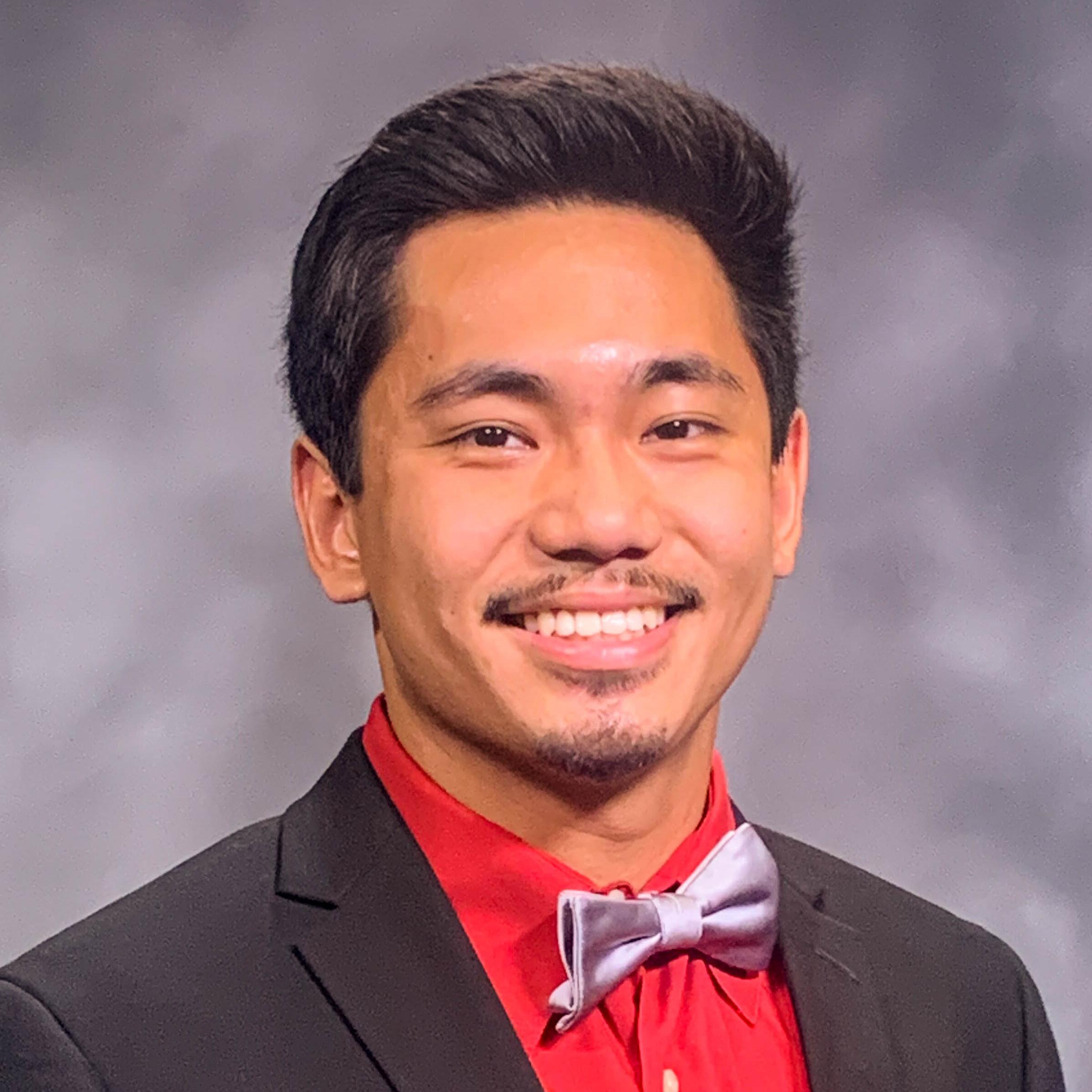 head and shoulders of man in red shirt, suit jacket and bow tie