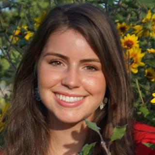 head and shoulders photo of Grace Hand with flowers in background