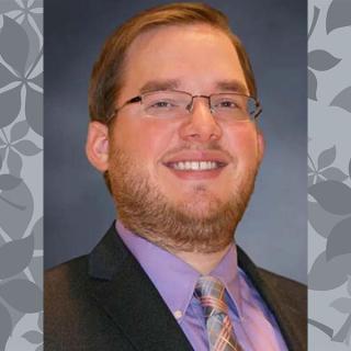 man with glasses suit purple shirt & tie