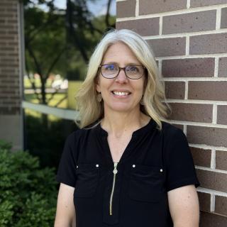women in black shirt and glasses in front of brick building
