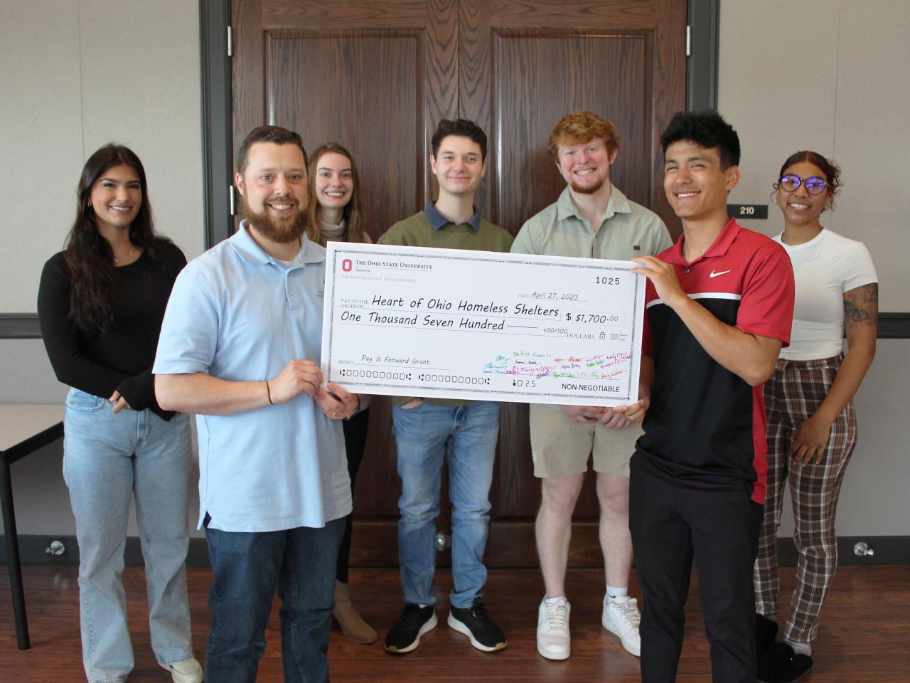 group of people holding up oversized check and smiling