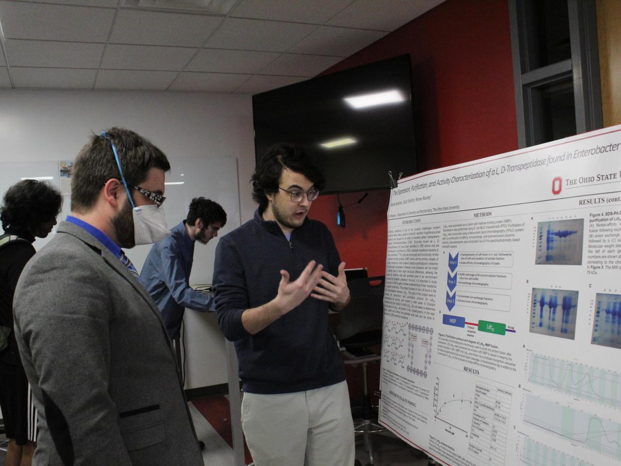 student presents their research poster to faculty