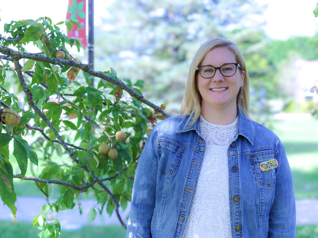 Woman in glasses and jean jacket in front of Buckeye tree