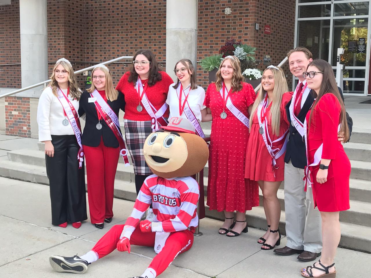 closer image group with mascot outside steps of building