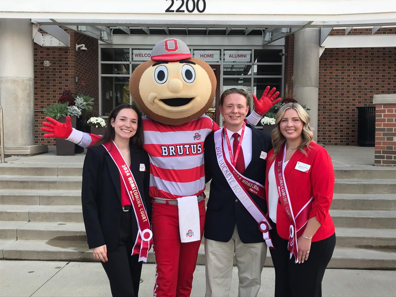 two women and one man in red and black dress clothes with mascot