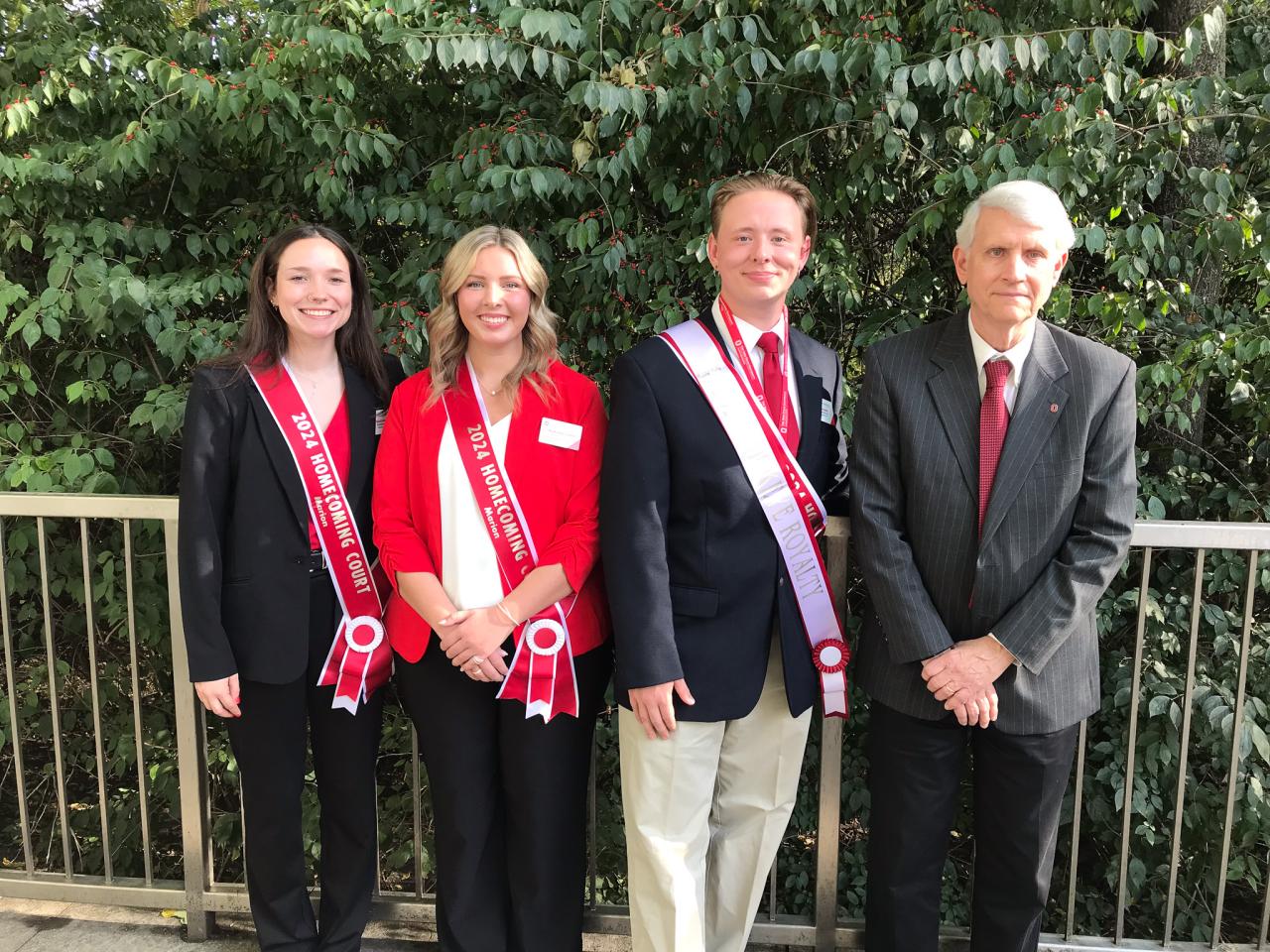 Three students with sashes pose with Dean of campus