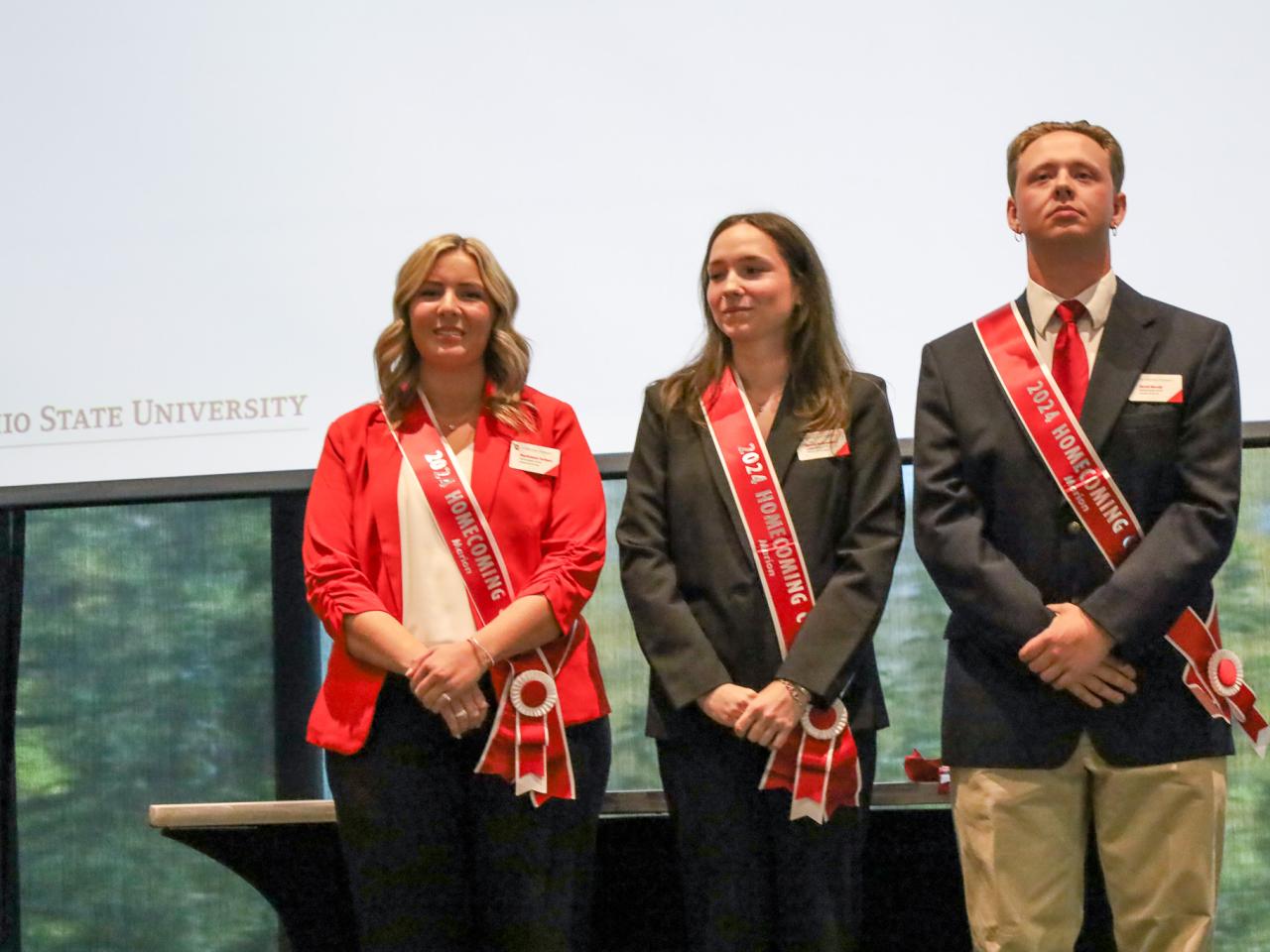 three dressed in red and black with sashes in front of white screen
