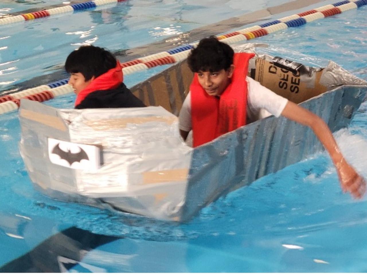 middle schoolers floating in a cardboard boat