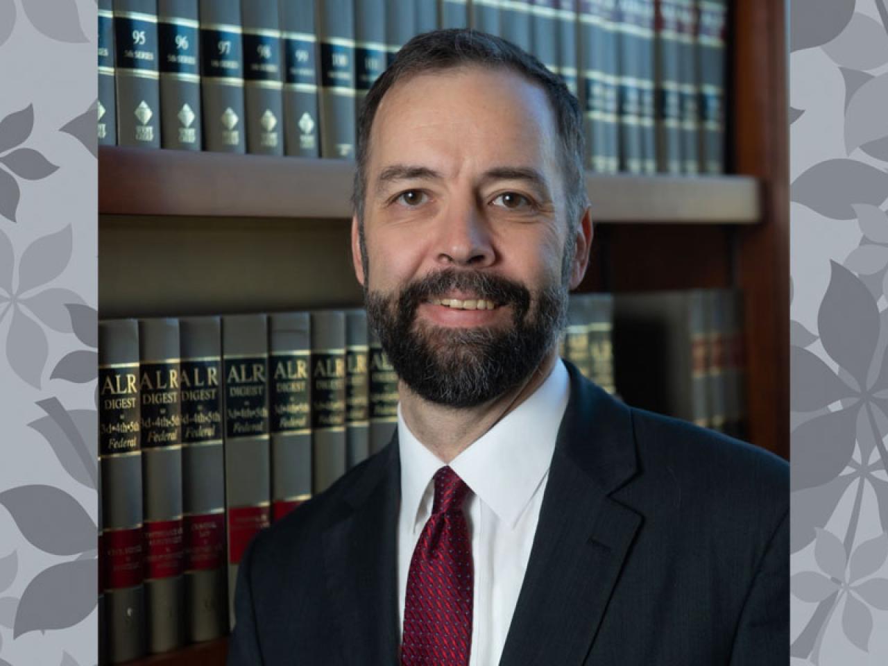 man in suit and tie, beard in front of law books