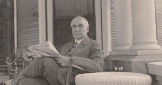 President Warren G. Harding sitting on his front porch in Marion, Ohio reading the newspaper