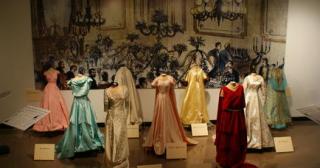 Old ballroom gowns hanging on forms in a gallery