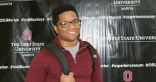 Trent Ramsey posing with book bag in front of OSUMarion background
