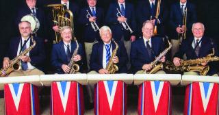 eleven member big band sitting with instruments in front of red, white, blue band stand