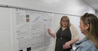 student presents their research poster to faculty