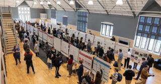 Large hall with presenters and research posters