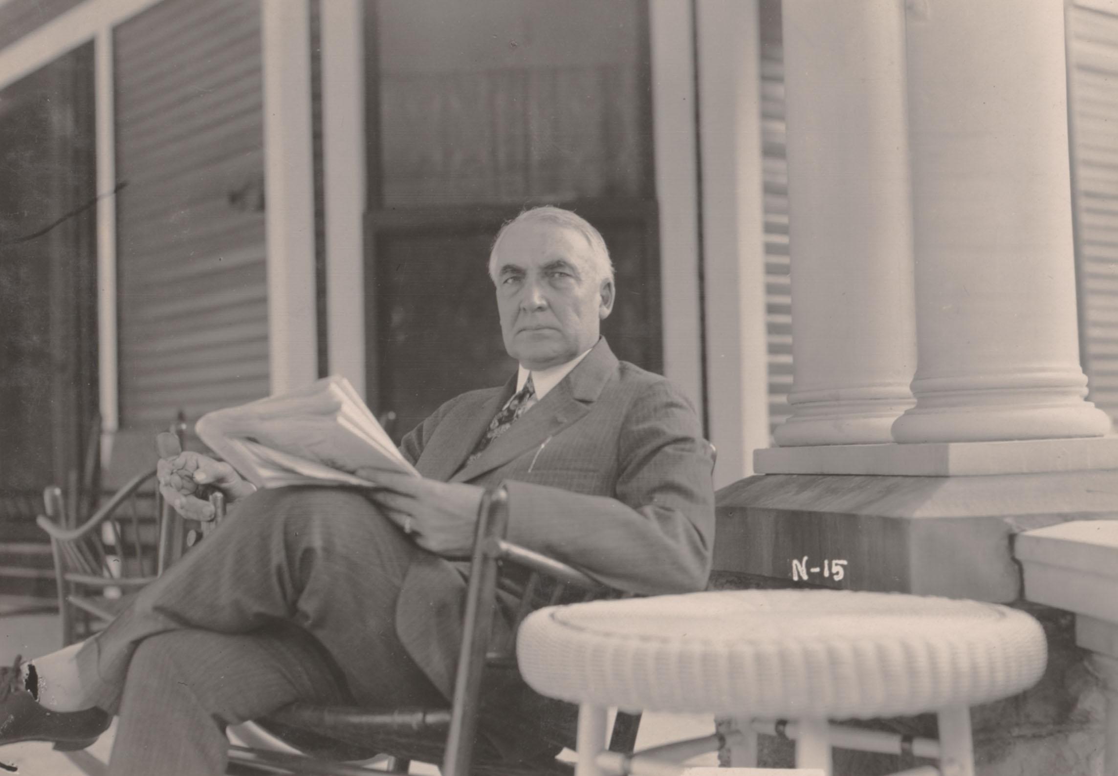 President Warren G. Harding sitting on his front porch in Marion, Ohio reading the newspaper