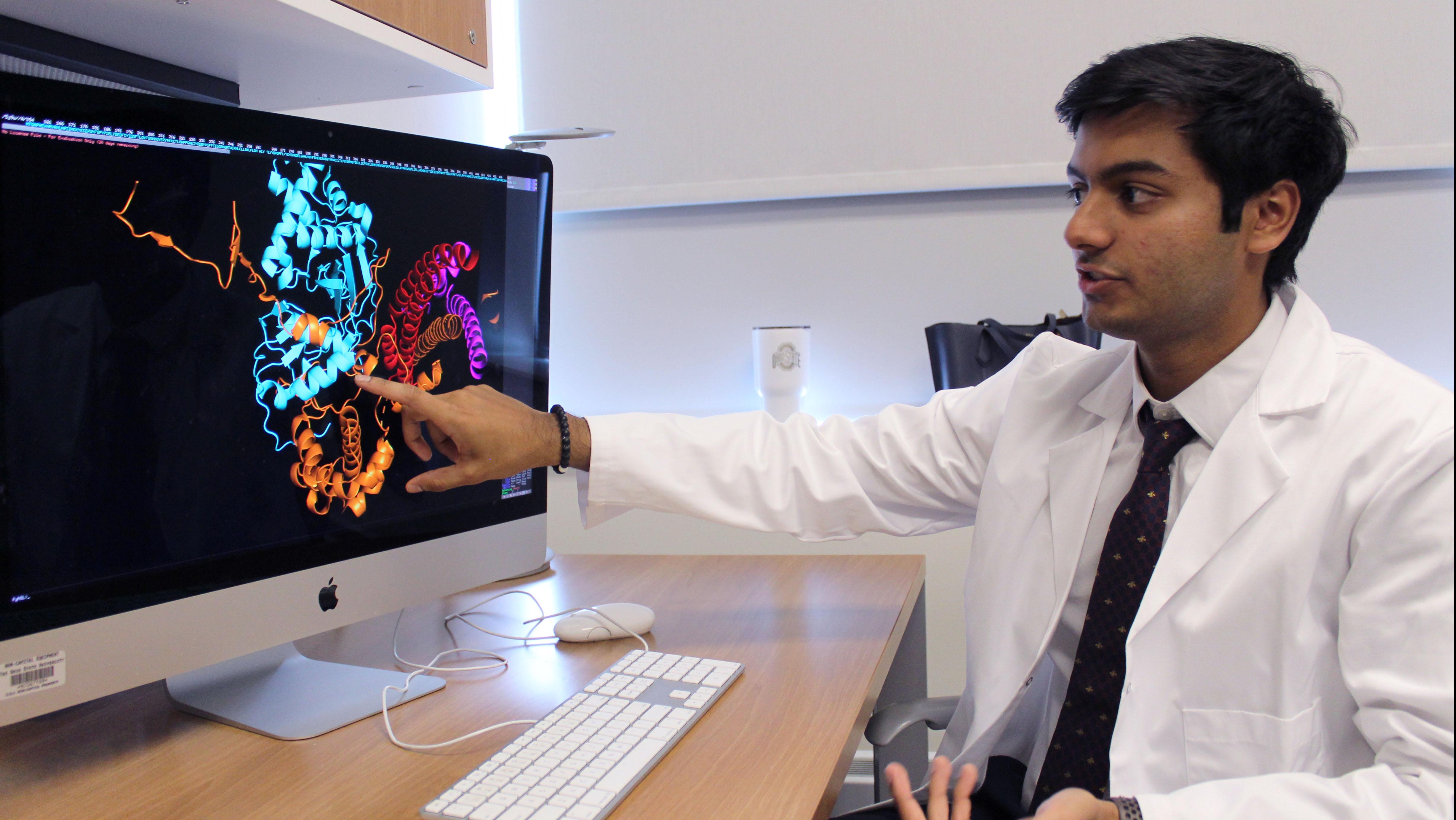 Biology major Shayaan Rasheed next to his research