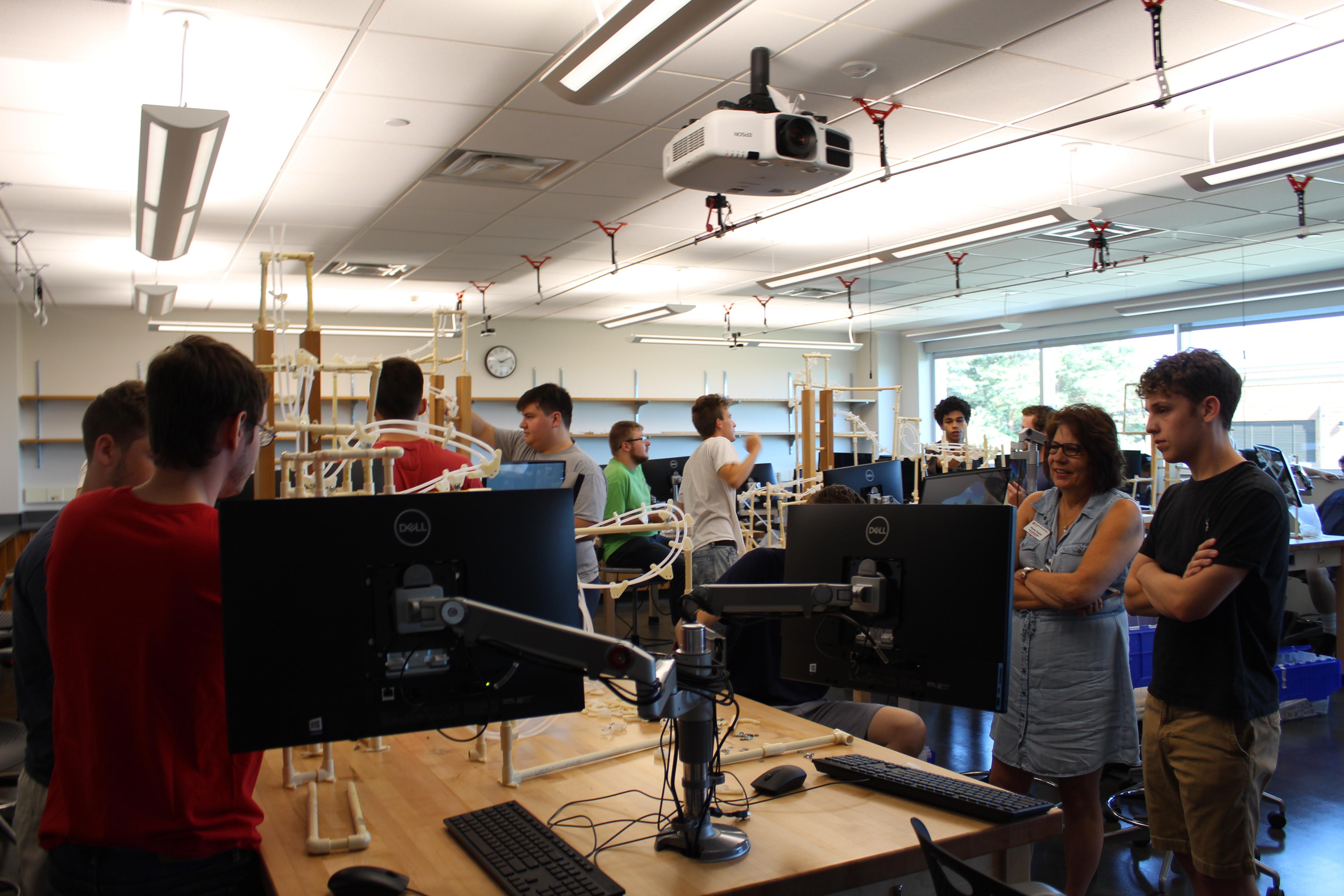 a wide shot photo of an entire classroom of engineering students working on rollercoaster models