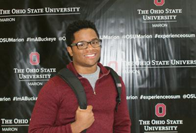 Trent Ramsey posing with book bag in front of OSUMarion background