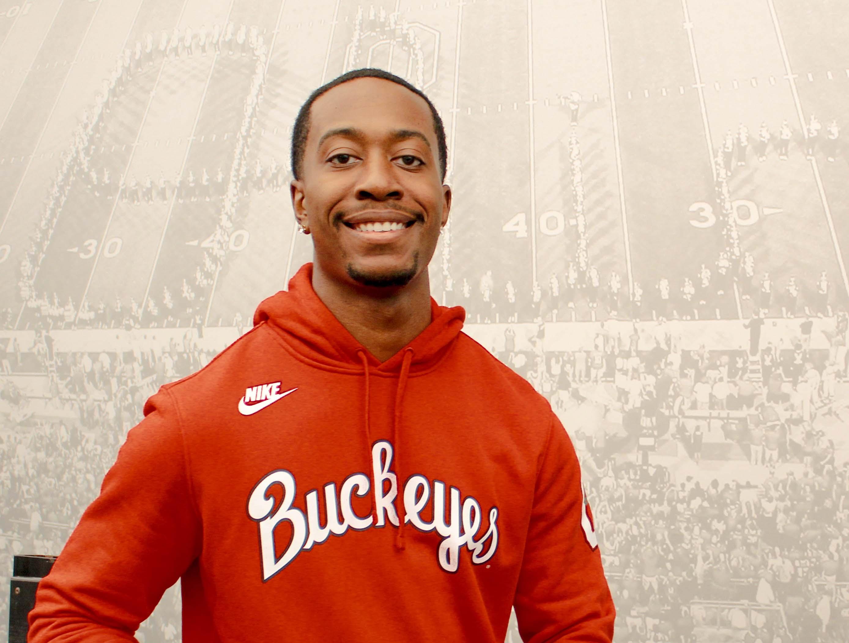 Man in red log hoodie in front of script Ohio picture