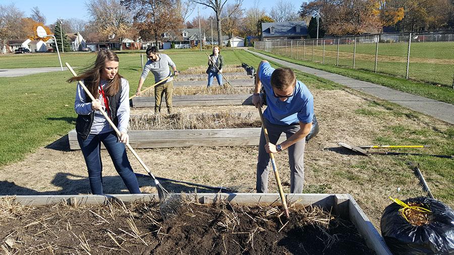 four students of The Ohio State University at Marion raking and digging in garden