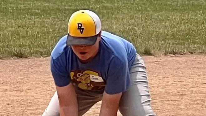 young baseball player in yellow and blue reaches down to make a catch