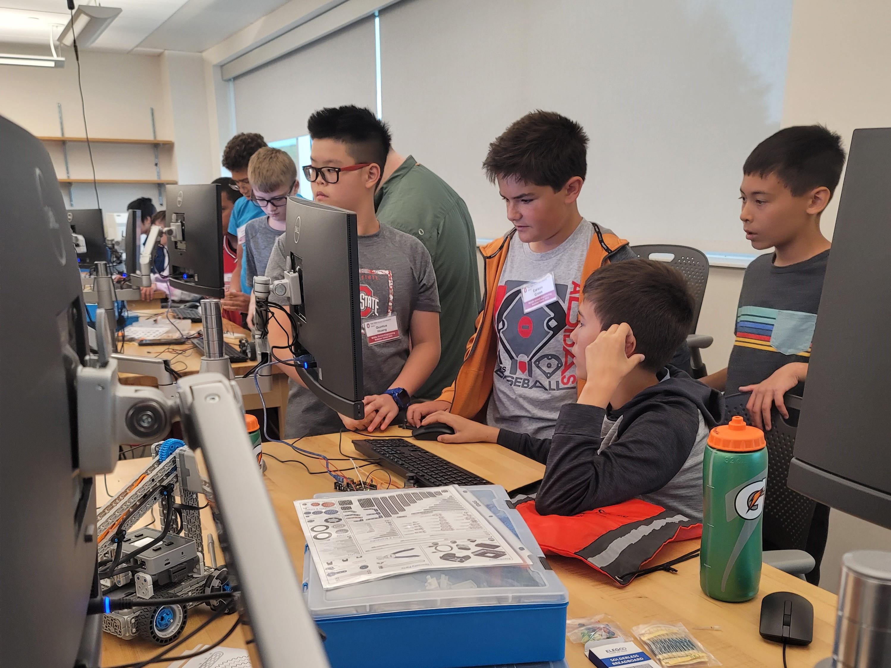 middle school students working at a computer on a robot