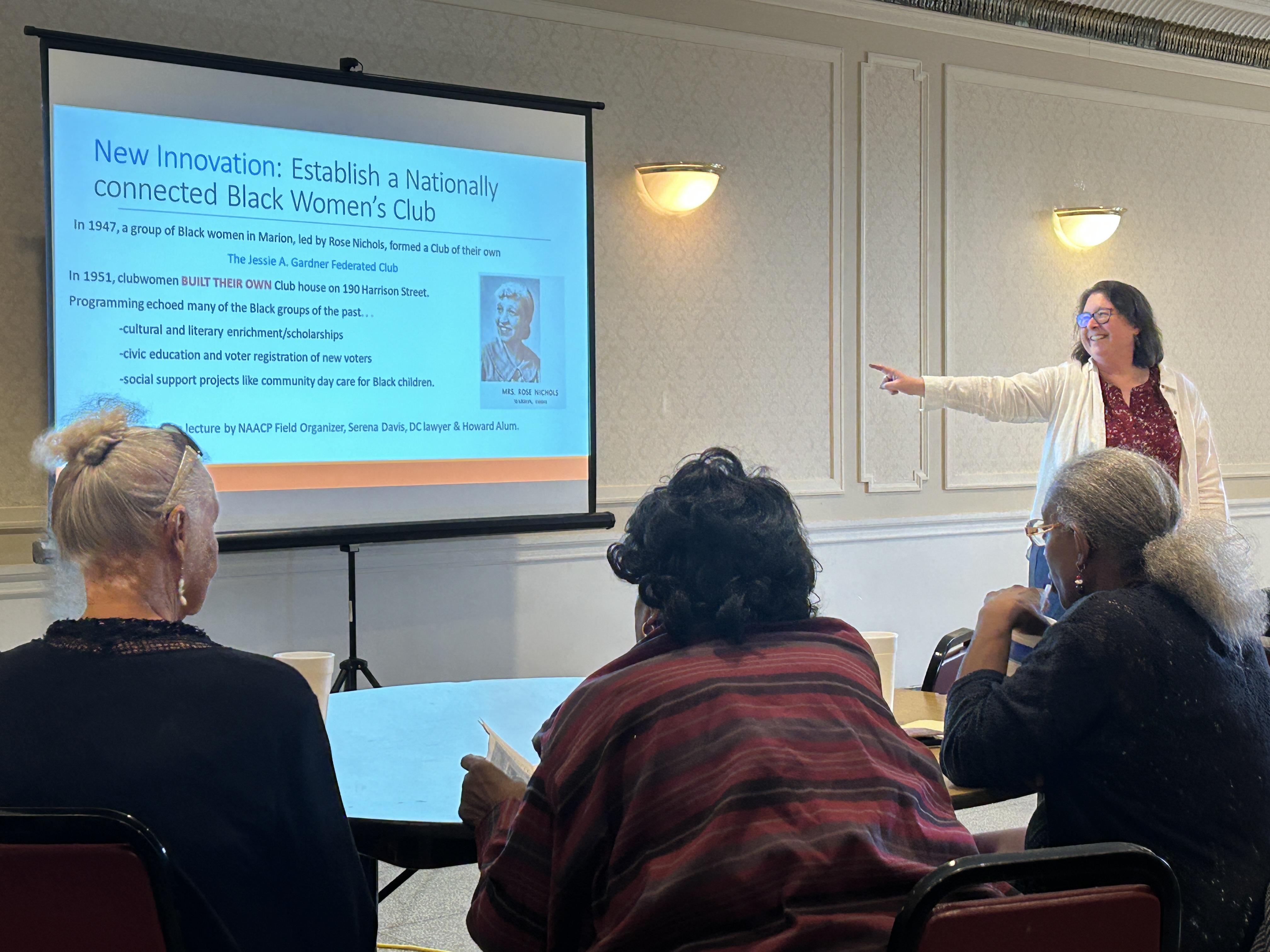 Woman presenting history lecture to room of community members