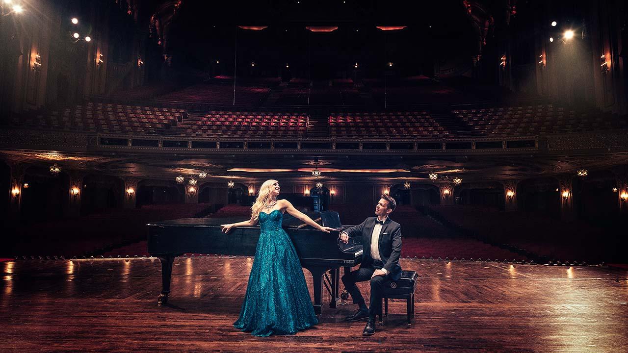 man and woman in dance pose on stage in front of piano