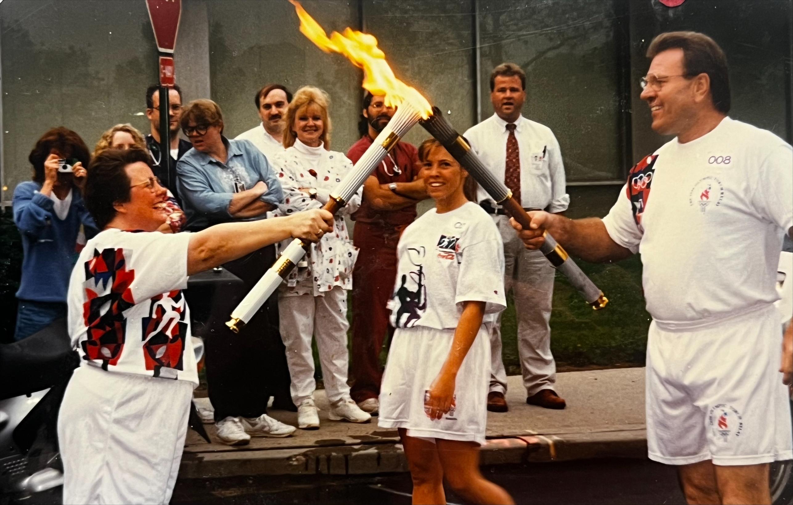 Woman lighting Olympic torch from male torch carrier