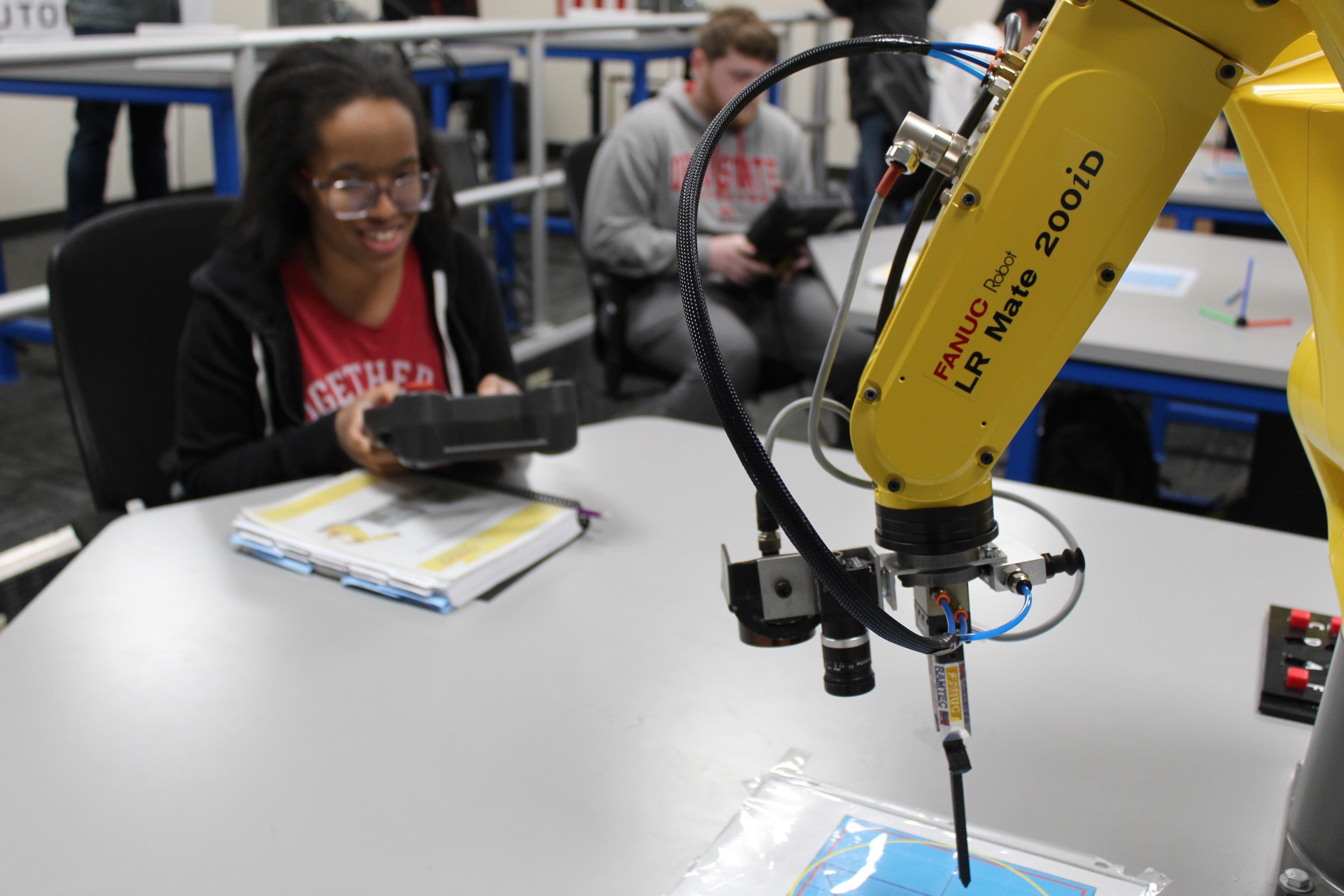 Young woman in glasses controls robot arm