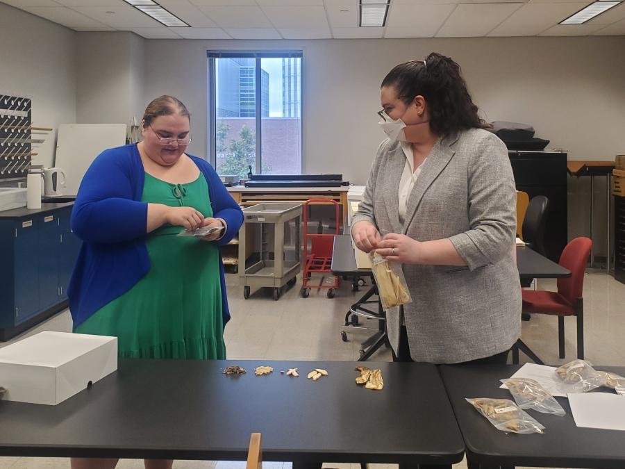 Two women examine Chinese herbs in the classroom