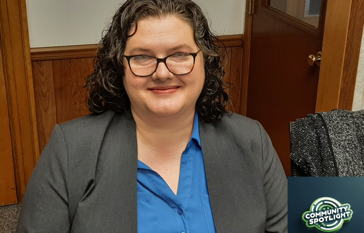 woman in blazer, blue blouse, glasses smiling at camera