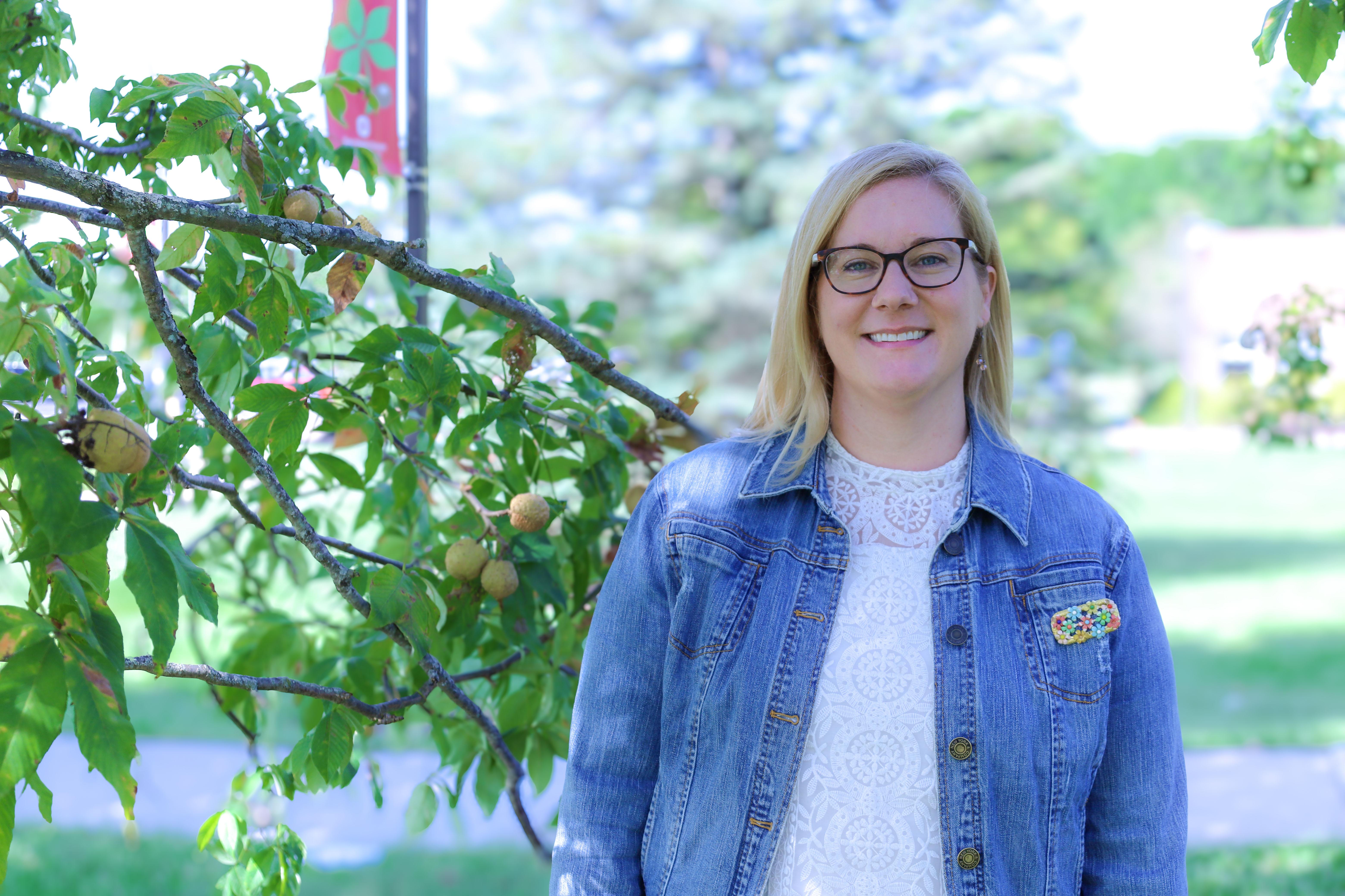 Woman in glasses and jean jacket in front of Buckeye tree