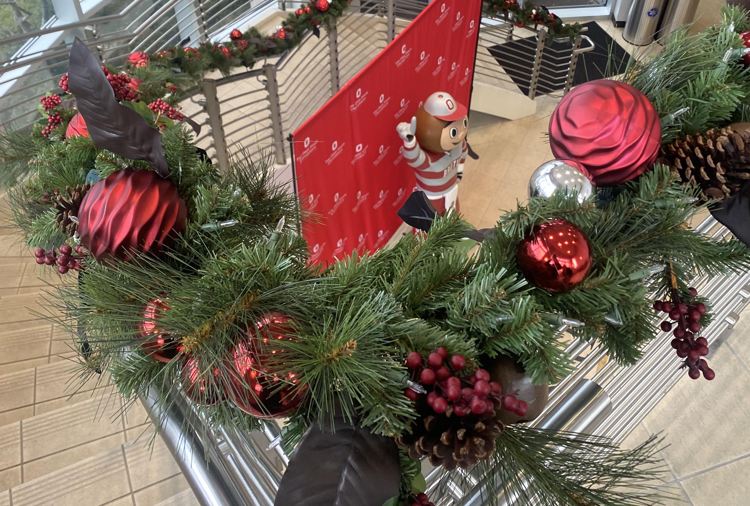 pine garland running up stair rail with Brutus Buckeye statue in background