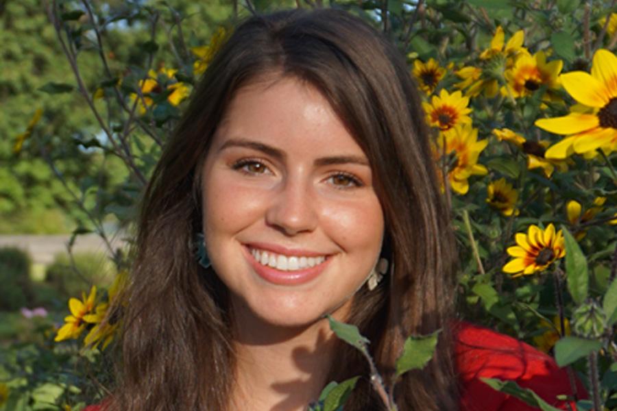 head and shoulders photo of Grace Hand with flowers in background